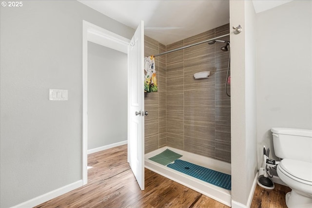 bathroom featuring a tile shower, hardwood / wood-style floors, and toilet