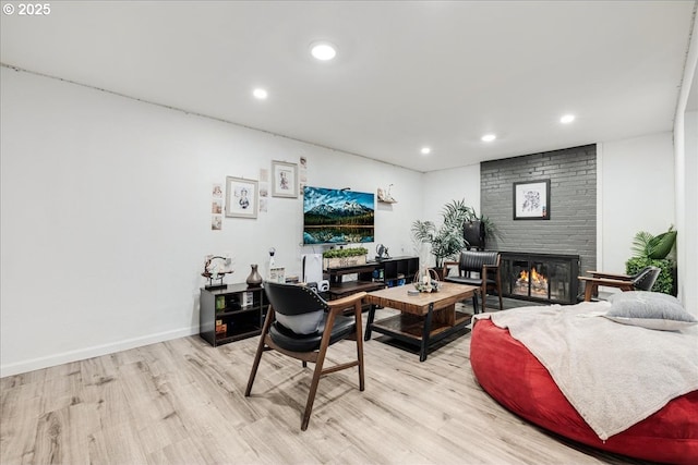 living room with a brick fireplace and light hardwood / wood-style floors