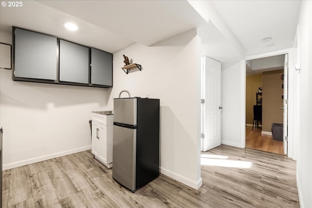 kitchen with light hardwood / wood-style flooring, stainless steel fridge, and white cabinets