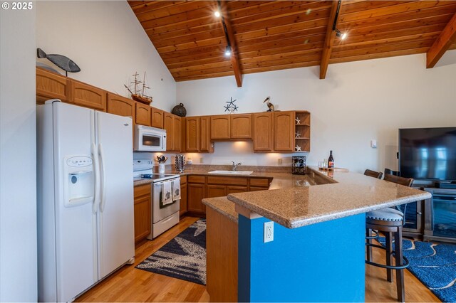 1323 Village Loop, Bandon, OR 97411 - kitchen featuring white appliances, a wood ceiling with exposed beams, a peninsula, a breakfast bar, and light wood-style floors