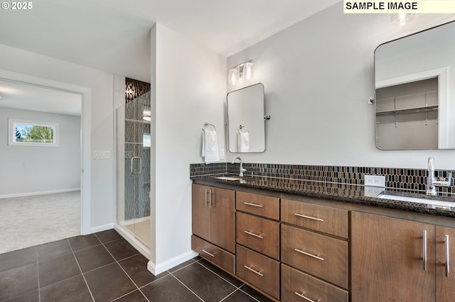 bathroom with double vanity, a shower stall, tile patterned flooring, and a sink