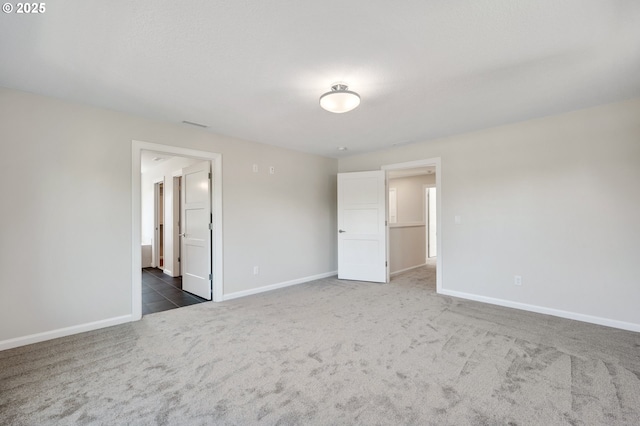 unfurnished bedroom with ensuite bath, baseboards, and carpet flooring