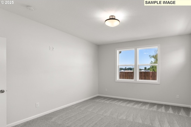 carpeted empty room featuring baseboards