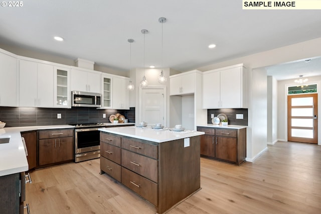 kitchen with backsplash, stainless steel appliances, light wood finished floors, and white cabinets