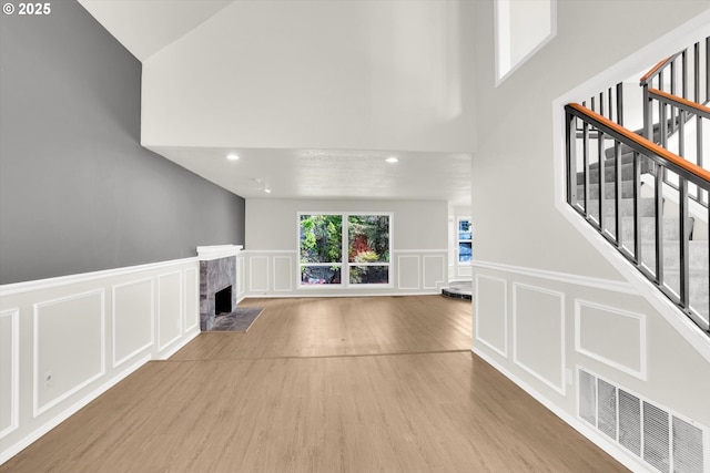 19915 SW Celebrity St, Beaverton, OR 97078 - unfurnished living room featuring visible vents, stairs, a decorative wall, a fireplace, and high vaulted ceiling