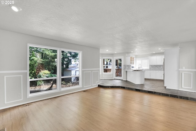 19915 SW Celebrity St, Beaverton, OR 97078 - unfurnished living room with a decorative wall, a textured ceiling, visible vents, dark wood-style floors, and recessed lighting
