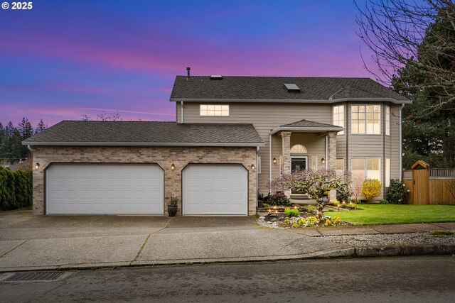 traditional home featuring concrete driveway, fence, an attached garage, a shingled roof, and a lawn