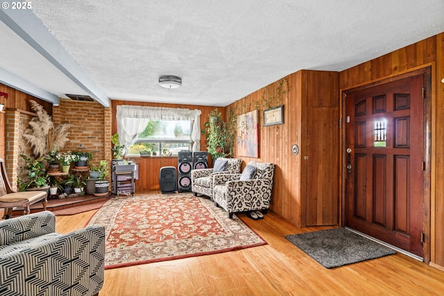 living room featuring beam ceiling, a textured ceiling, and wood-type flooring