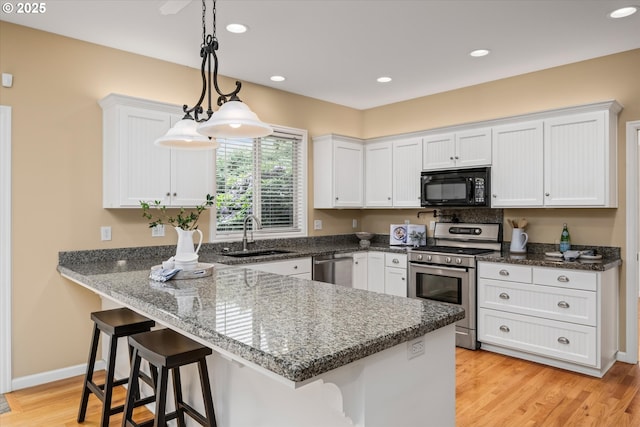 2053 Lakeview Dr, Eugene, OR 97408 - kitchen featuring appliances with stainless steel finishes, white cabinetry, a kitchen breakfast bar, a peninsula, and light wood-style floors