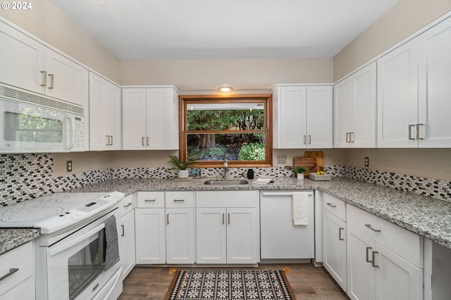 kitchen featuring white appliances, a sink, wood finished floors, white cabinets, and light stone counters