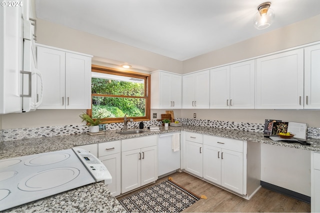kitchen with a sink, range, light wood-type flooring, white cabinetry, and light stone countertops