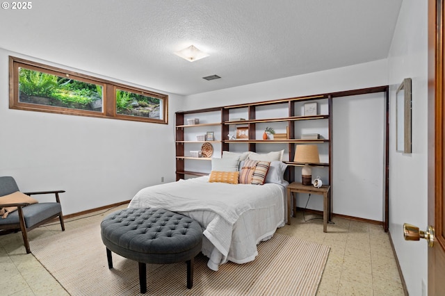 bedroom with light flooring, baseboards, and a textured ceiling