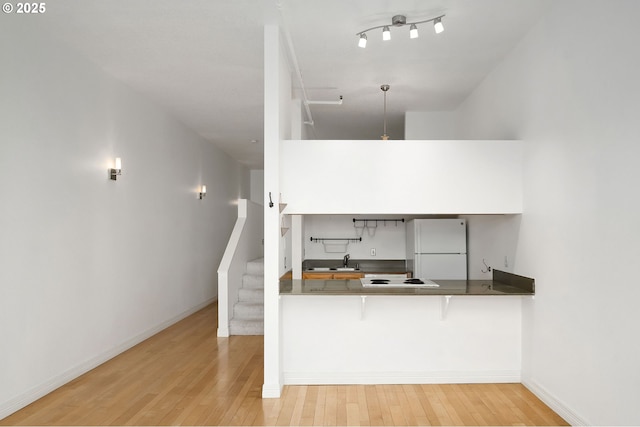 1910 SW 18th Ave Unit 34, Portland, OR 97201 - kitchen featuring freestanding refrigerator, hardwood / wood-style flooring, a kitchen bar, and a peninsula