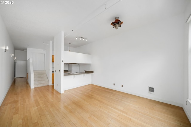 1910 SW 18th Ave Unit 34, Portland, OR 97201 - unfurnished living room with light wood finished floors, stairway, and rail lighting