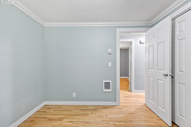 unfurnished room featuring light wood-type flooring, baseboards, and crown molding