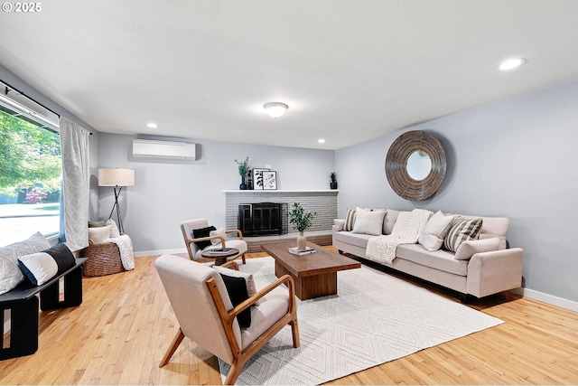 living room featuring a wall mounted AC, wood finished floors, baseboards, a fireplace, and recessed lighting