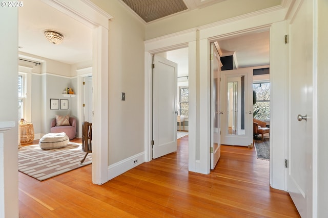 hallway with visible vents, baseboards, a healthy amount of sunlight, and light wood-style flooring