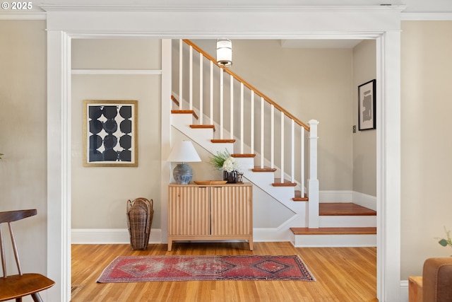 staircase with ornamental molding, baseboards, and wood finished floors