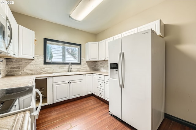 kitchen featuring white appliances, sink, decorative backsplash, and white cabinets