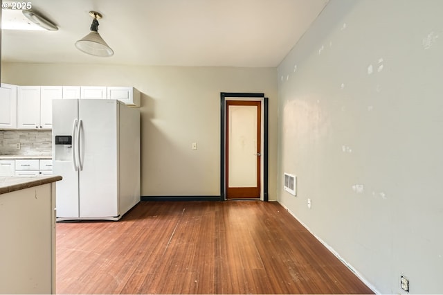 kitchen with backsplash, white refrigerator with ice dispenser, light hardwood / wood-style floors, and white cabinets