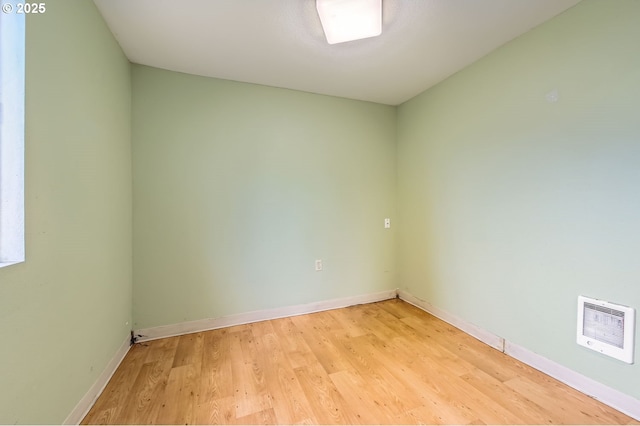 empty room with heating unit and light hardwood / wood-style flooring