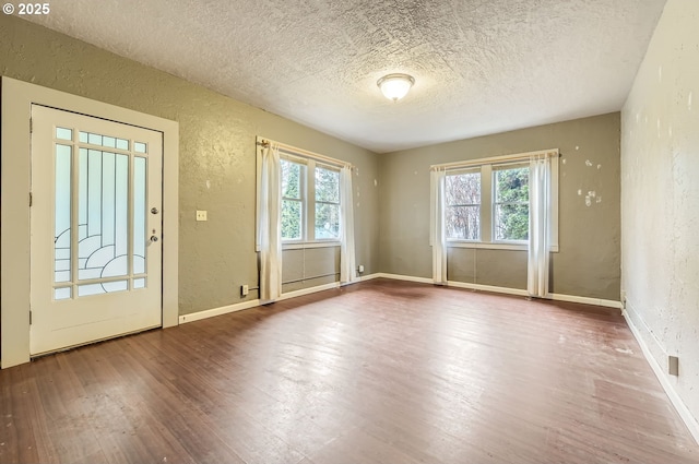 doorway with a wealth of natural light, hardwood / wood-style floors, and a textured ceiling