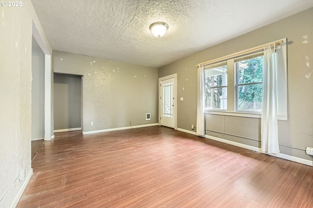 empty room featuring wood-type flooring and a textured ceiling