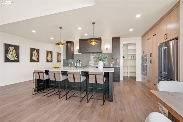 750 N V St, Washougal, WA 98671 - kitchen featuring appliances with stainless steel finishes, light countertops, light wood-style flooring, a kitchen breakfast bar, and recessed lighting