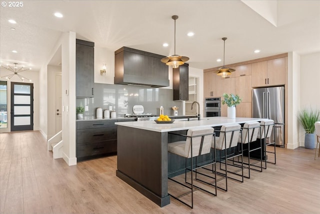 750 N V St, Washougal, WA 98671 - kitchen featuring stainless steel appliances, custom range hood, light countertops, modern cabinets, and light wood-type flooring
