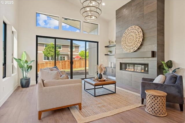750 N V St, Washougal, WA 98671 - living area with a towering ceiling, wood finished floors, a tiled fireplace, baseboards, and a chandelier