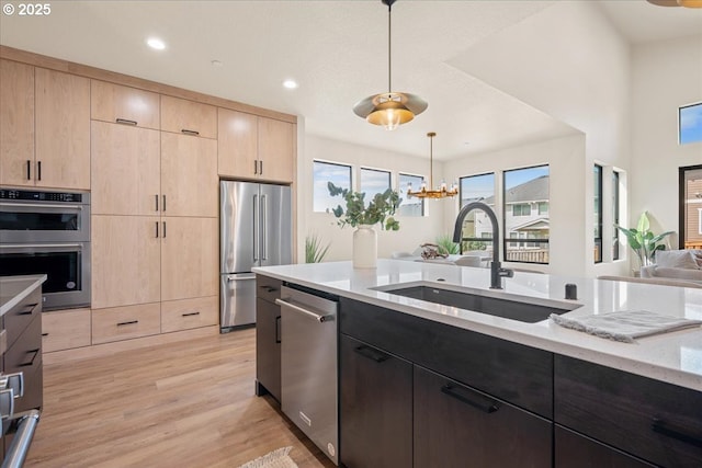 750 N V St, Washougal, WA 98671 - kitchen featuring light brown cabinetry, appliances with stainless steel finishes, a sink, light stone countertops, and light wood-style flooring