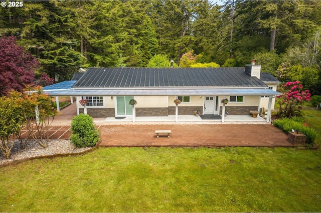 88771 Tokyo Ln, Bandon, OR 97411 - rear view of house featuring covered porch, a chimney, a lawn, and stone siding
