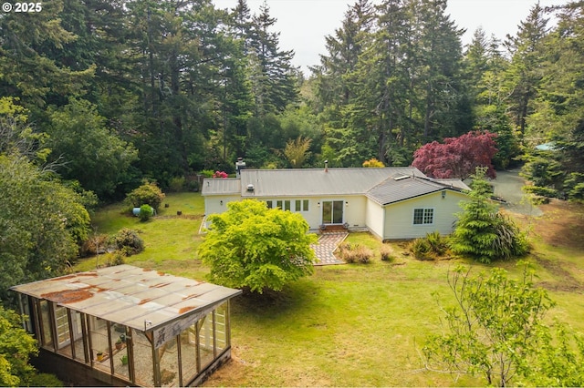 88771 Tokyo Ln, Bandon, OR 97411 - back of house with a lawn, a metal roof, and a wooded view