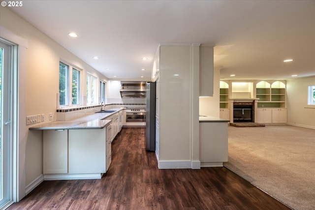 88771 Tokyo Ln, Bandon, OR 97411 - kitchen featuring oven, a glass covered fireplace, white cabinets, recessed lighting, and dark wood-style flooring