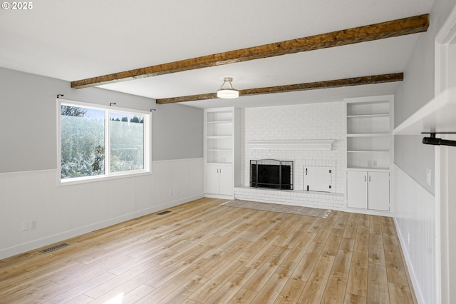 unfurnished living room with light hardwood / wood-style flooring, built in features, and a fireplace