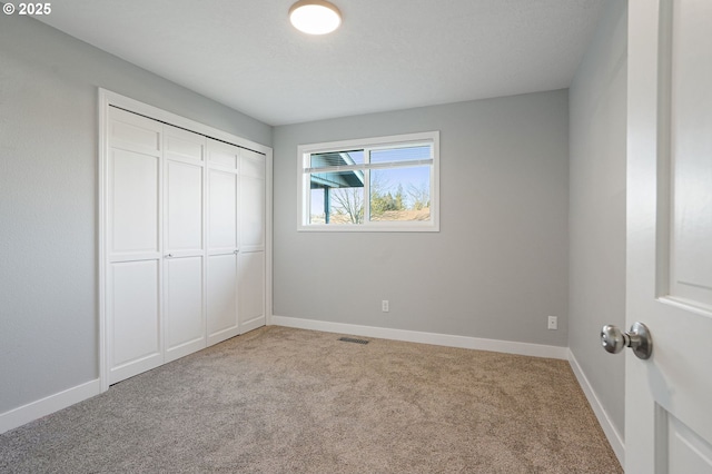 unfurnished bedroom with a closet and light colored carpet