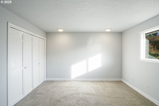 unfurnished bedroom featuring a textured ceiling, a closet, and carpet