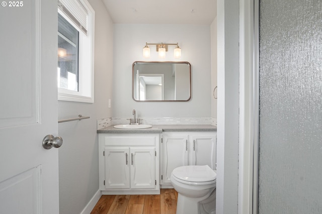 bathroom with toilet, wood-type flooring, and vanity