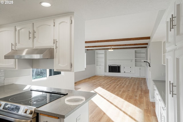 kitchen with stainless steel range with electric cooktop, a fireplace, white cabinetry, beamed ceiling, and light wood-type flooring