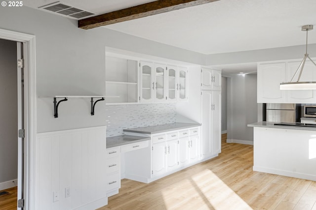 kitchen featuring white cabinets, light wood-type flooring, decorative light fixtures, and beamed ceiling