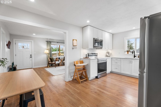 kitchen featuring tasteful backsplash, stainless steel appliances, light wood-type flooring, and a wealth of natural light