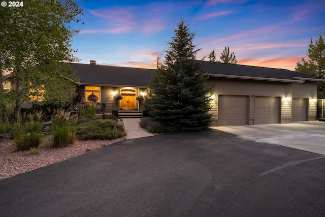 6904 SW Joshua Ct, Powell Butte, OR 97753 - view of front of house with concrete driveway, a garage, and a chimney