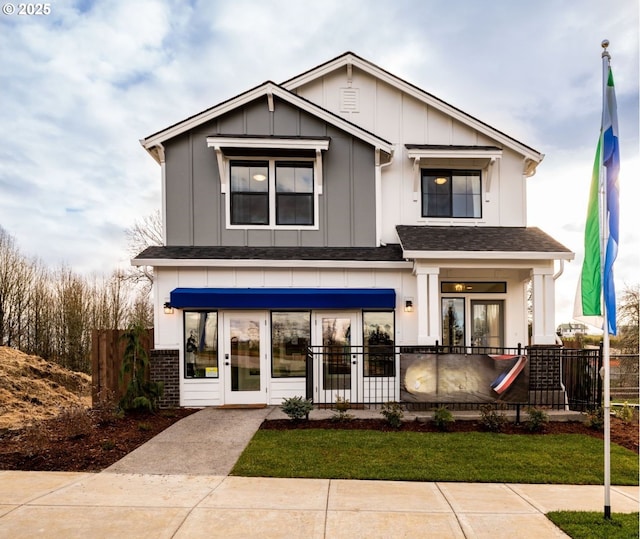 view of front of property featuring a fenced front yard, a shingled roof, board and batten siding, and brick siding