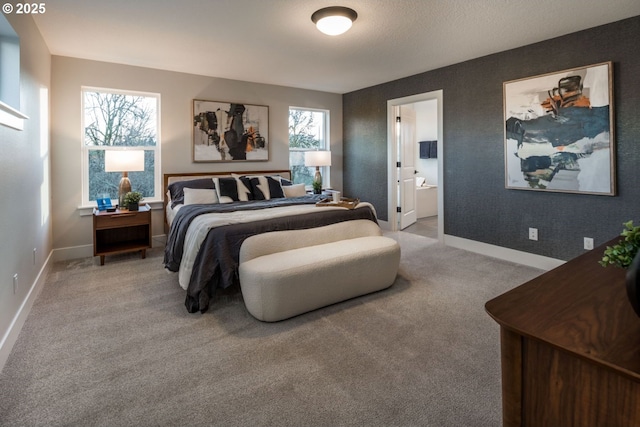 bedroom with baseboards, ensuite bathroom, and light colored carpet