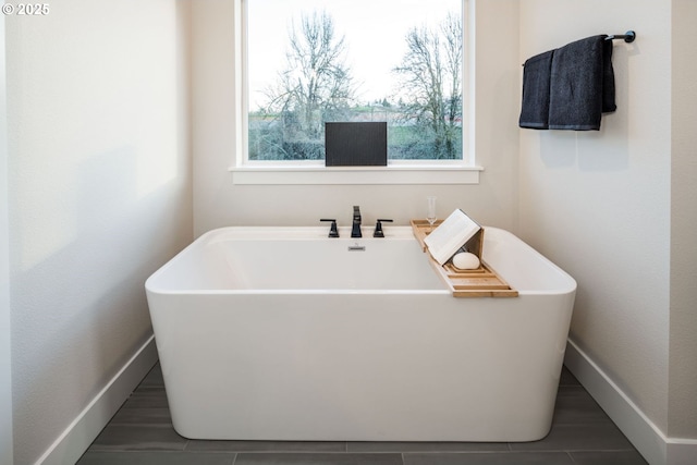 full bathroom featuring a freestanding tub and baseboards