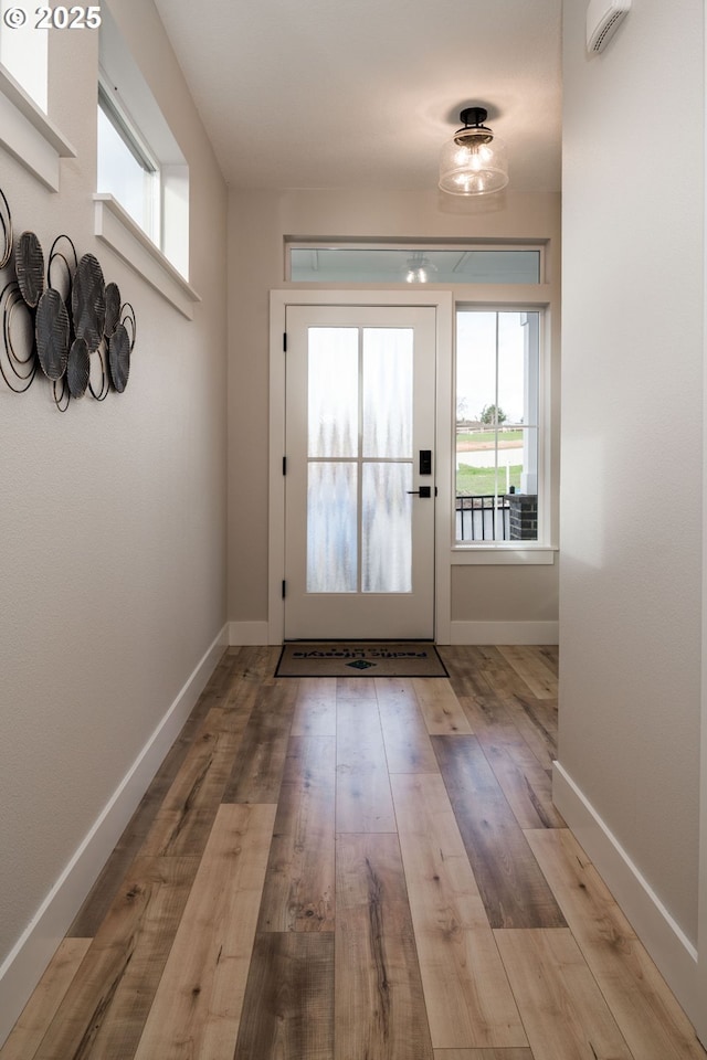 doorway with light wood-type flooring and baseboards