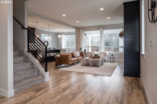 living room featuring stairs, recessed lighting, baseboards, and light wood-style floors