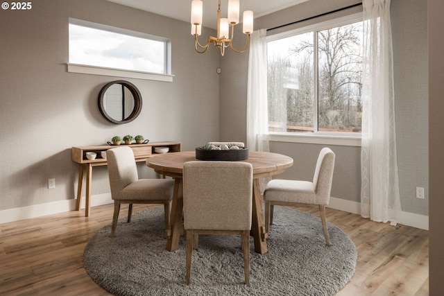 dining room with a chandelier, light wood-type flooring, and baseboards