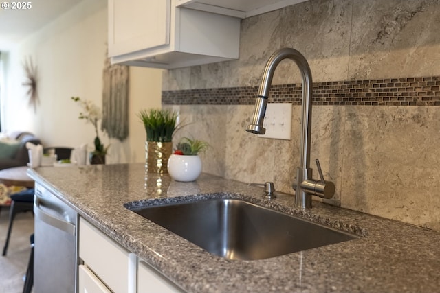 kitchen featuring white cabinetry, dark stone counters, a sink, dishwasher, and backsplash