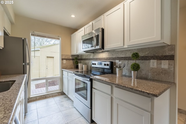 kitchen with stainless steel appliances, tasteful backsplash, light tile patterned flooring, and white cabinetry